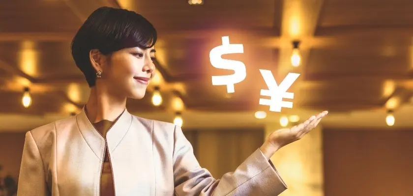 ドルと円のシンボルを手のひらに浮かべる女性ビジネスパーソン