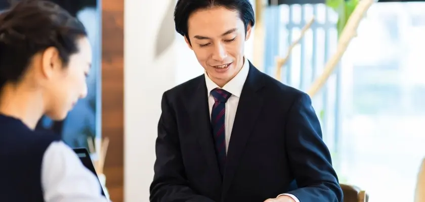 スーツ姿の男性が顧客と話す不動産営業のイメージ