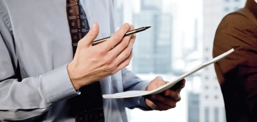 Close-up of a businessman’s hands holding a pen and documents during a meeting