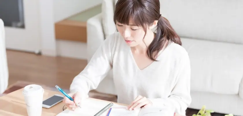 ノートに勉強する女性と机上のコーヒーカップ