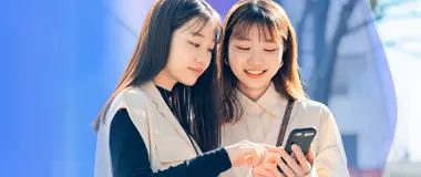 Two young professionals sharing a smartphone – Hays Japan referral campaign and job search support.