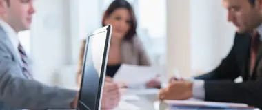 Business people sitting at a table in a meeting with a laptop in the foreground